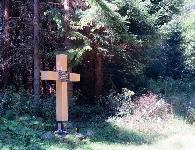na desce připevněné ke kříži je nápis: In memoriam. Na památku bývalé obce Fláje.